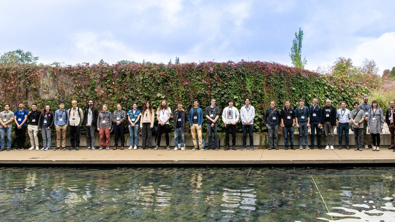 Group picture of researchers in front of an evergreen fence.